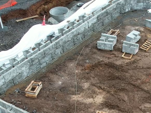 Gravity retaining wall with manhole pipe installed behind the wall.
