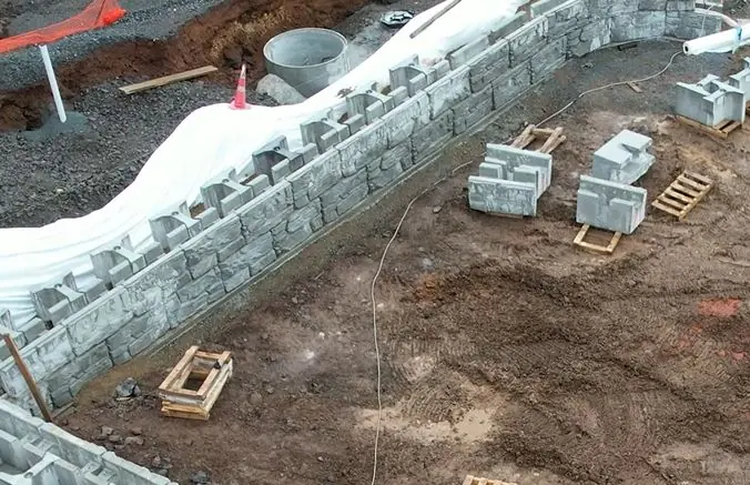 Gravity retaining wall with manhole pipe installed behind the wall.