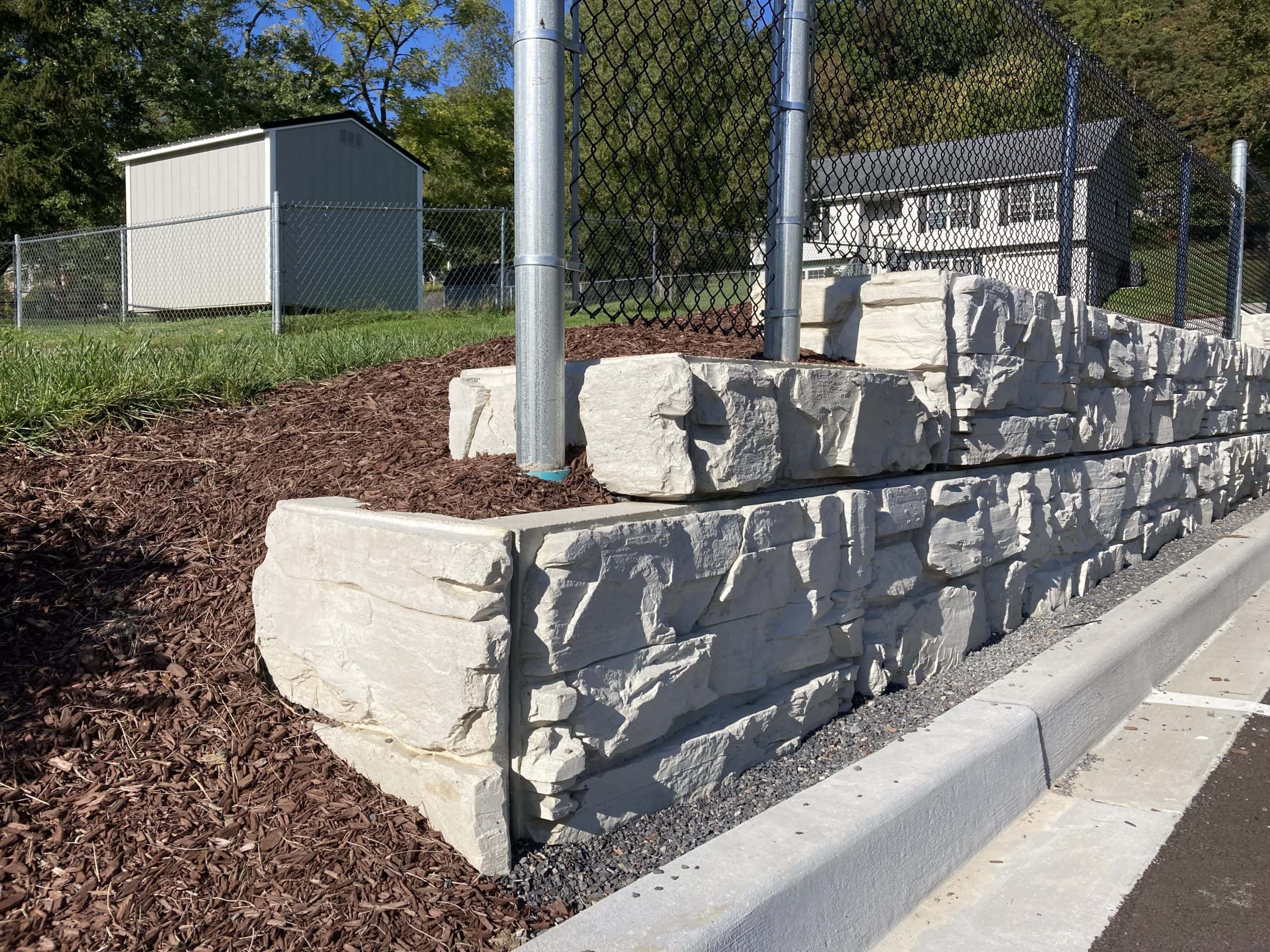 Retaining wall with fence posts atop MagnumStone wall.
