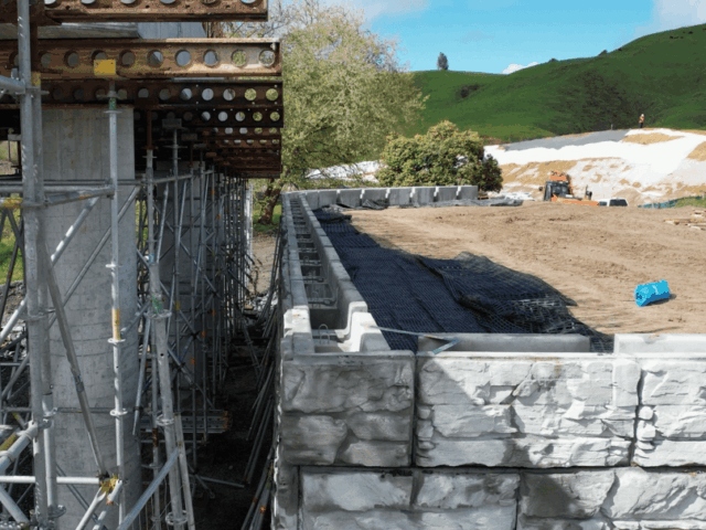 Precision placement of MagnumStone blocks for bridge abutment.