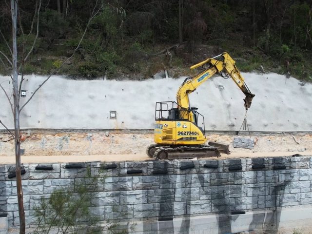 Equipment carrying MagnumStone blocks on construction site for installation.